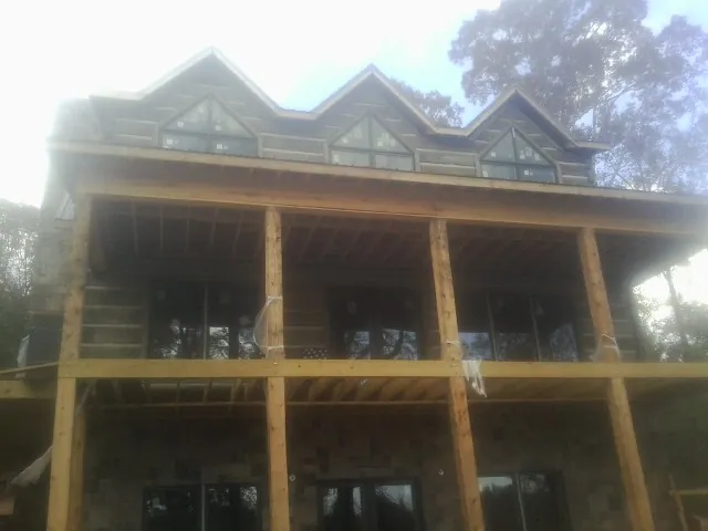 Dormers and porch framing on a large log home under construction — Roof Coating work by our crew in Lomira