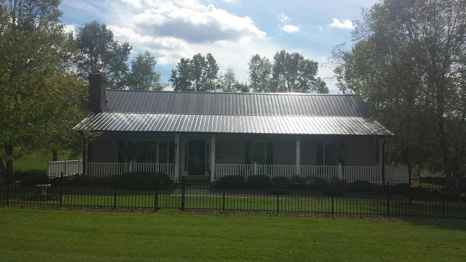Gray metal roof on a brick ranch with a full width front porch — Gutter Guard Installation work by our crew in Lomira