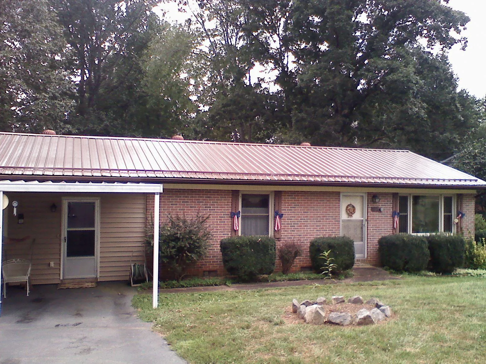 Bronze metal roof and carport on a brick ranch home — Roof Repair work by our crew in Lomira