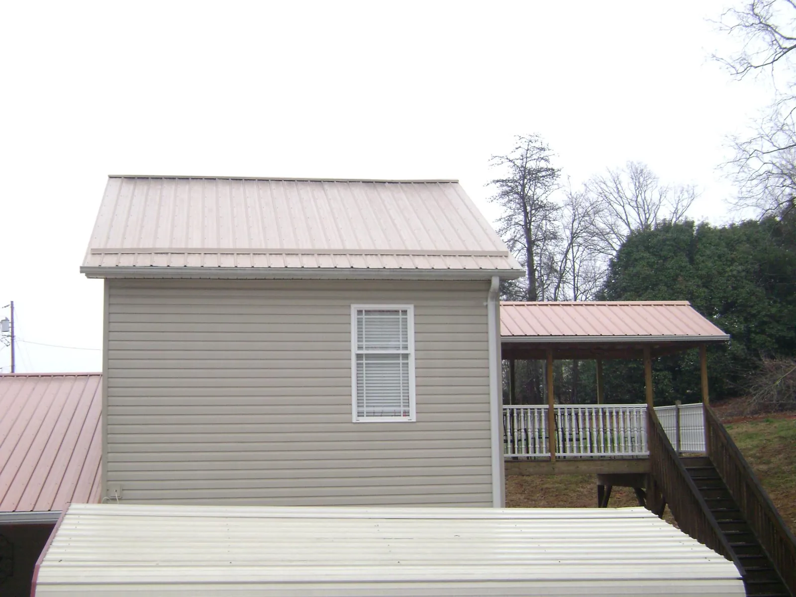 Tan metal roofs on a two story addition and attached porch, from a Roof Replacement job in Lomira