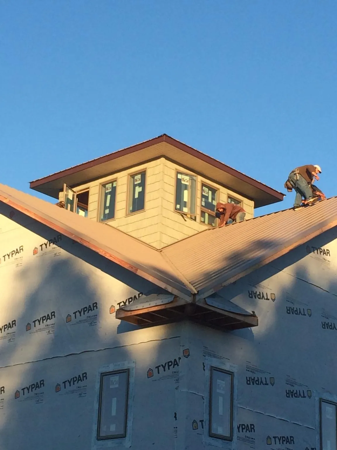 Roofers working around a rooftop cupola on a new metal roof at sunset — Roof Waterproofing in Lomira by Roofing Brothers